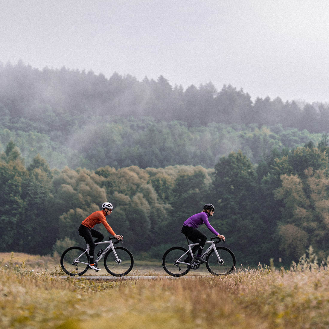 two guys riding on road bikes in autumn season and wearing Luxa insulated jackets